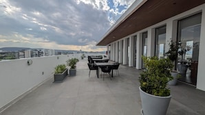 Una terraza en la azotea con zona de comedor, plantas en macetas y vistas de la ciudad.