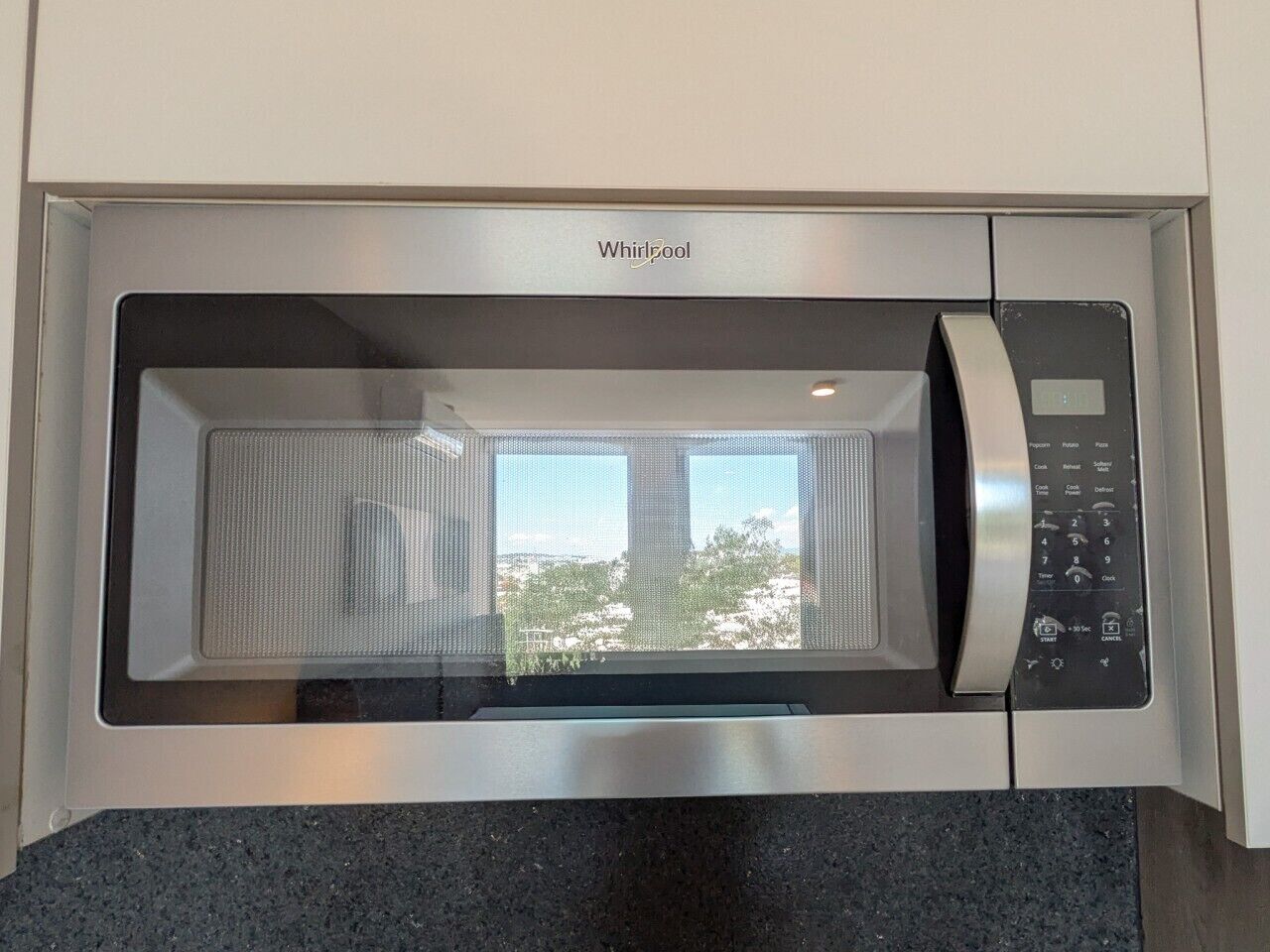 A Whirlpool microwave oven with a digital control panel and a window above the door.