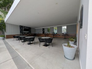 Un espace extérieur aménagé en terrasse, avec des tables et des chaises, un coin salon et des plantes en pot.