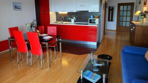 Una sala de estar moderna con una zona de comedor roja, una mesa de centro de vidrio y un sofá azul.