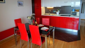 Una cocina moderna con armarios rojos y blancos, una encimera negra y un comedor con sillas rojas.