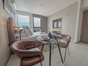 Una sala moderna con un sofá, una mesa de comedor de cristal y vistas a la ciudad.