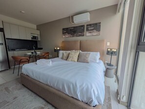 Habitación de hotel con cama, escritorio, silla y kitchenette.
