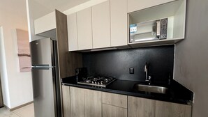A modern kitchen with a stainless steel refrigerator, a gas stove, and a microwave above the counter.