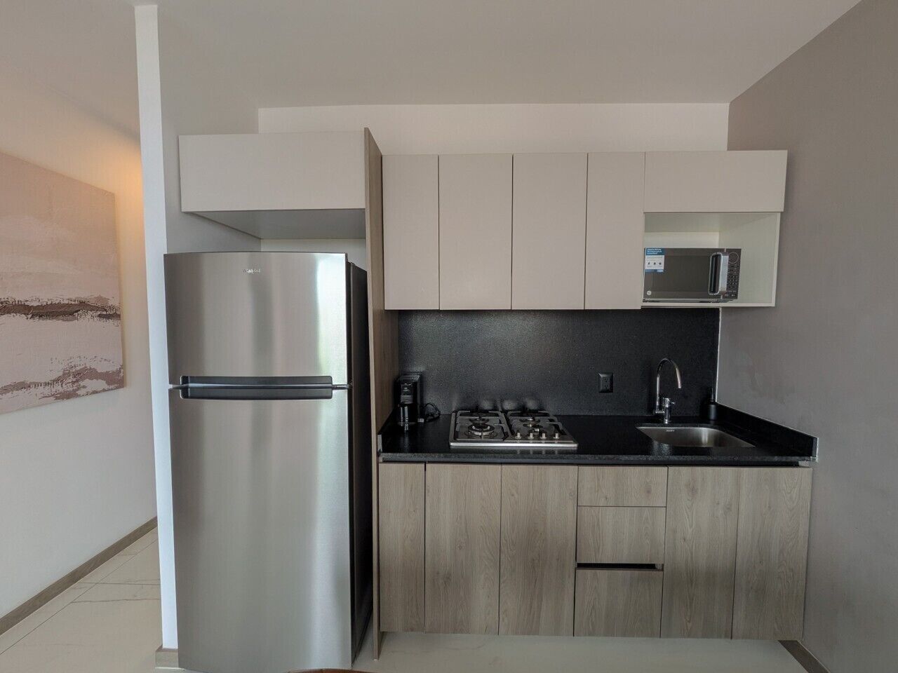Eine moderne Küche mit einem Edelstahlkühlschrank, einer Mikrowelle, einem Herd und Holzschränken.
