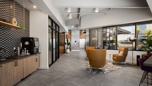 Un ufficio moderno con angolo cottura, postazioni di lavoro e ampie finestre che offrono vista sulla città.