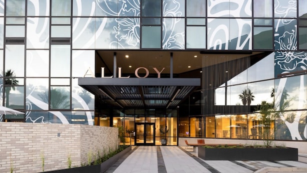 Un edificio moderno con facciata in vetro e la scritta “ALLLOY” ben visibile.