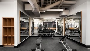 Una palestra con pareti a specchio, rastrelliere per pesi e attrezzature per l'allenamento.