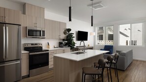 Una cucina moderna con elettrodomestici in acciaio inossidabile, un'isola spaziosa con sgabelli da bar e un televisore a schermo piatto montato a parete.