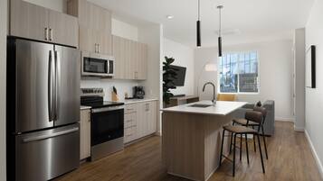 A modern kitchen with stainless steel appliances, a central island, and a dining area with bar stools.