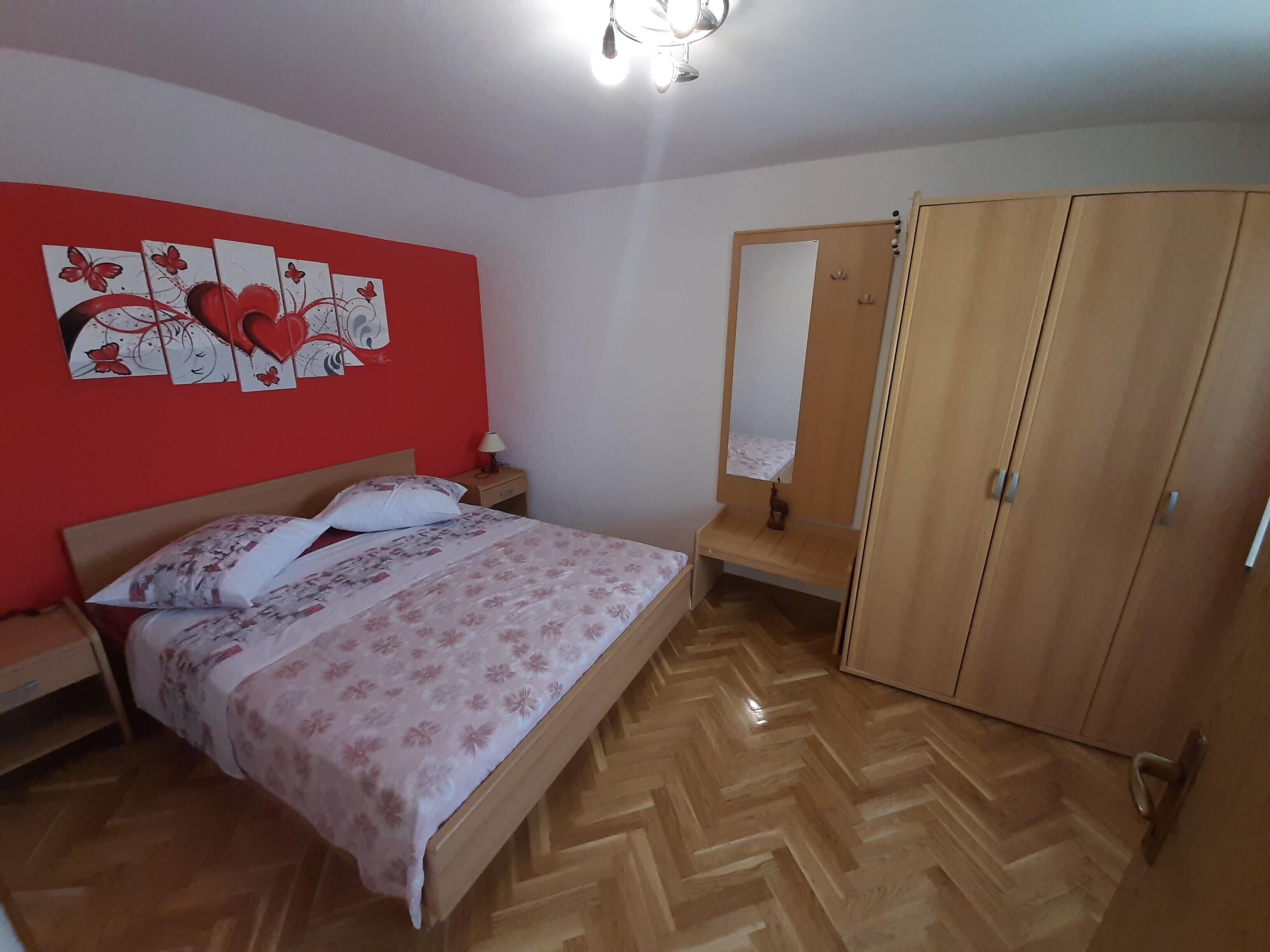 A bedroom with a wooden bed, a nightstand, a mirror, and a wardrobe.
