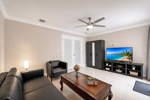 A living room with a sofa, armchair, coffee table, television, and a cabinet.