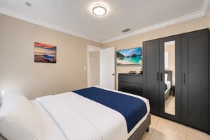 Une chambre à coucher avec un lit, une armoire, une commode et un tableau au mur.
