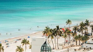 A beach with palm trees, umbrellas, and people. - Great Location Heated Pool near Hollywood Beach (Hollywood)