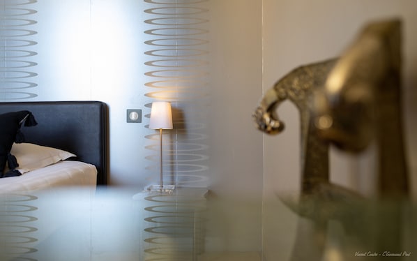 A hotel room with a bed, a lamp, and a decorative wall piece. - Hotel Restaurant Le Vinois (Caillac)