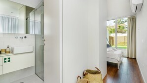 A modern bathroom with a glass shower, a white sink, and a visible emergency exit sign. - Bombarda Patio Oasis by LovelyStay (Porto)