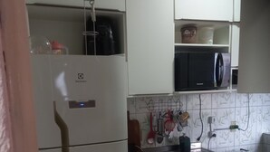 Une cuisine avec des armoires blanches, un four à micro-ondes encastré, un évier et une cuisinière.