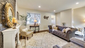 A living room with a fireplace, patterned furniture, and a large mirror. - 6 Mi to Downtown - Spacious Home in Pittsburgh! (Pittsburgh)