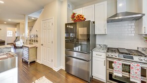 A spacious kitchen with stainless steel appliances, white cabinetry, and a marble countertop. - 6 Mi to Downtown - Spacious Home in Pittsburgh! (Pittsburgh)