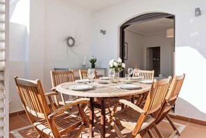 A round wooden table set for dining with chairs, a vase with flowers, and a wall-mounted decorative piece.
