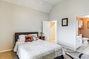 Una camera da letto con un letto grande, un comodino, una porta che dà su un bagno e un corridoio.