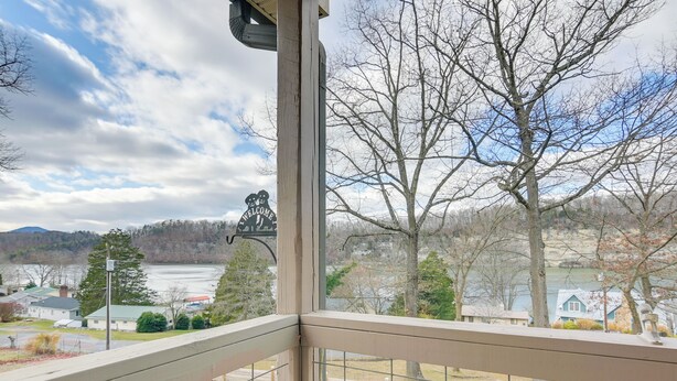 A view from a balcony with a metal railing, overlooking a lake, trees, and houses. - Apt w/ Lake Views - Day Trip to Virginia Tech! (Radford)