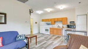 A compact living space with a kitchenette, a blue sofa, a brown armchair, and a small wooden table. - Apt w/ Lake Views - Day Trip to Virginia Tech! (Radford)
