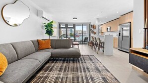 A modern living room with a grey sectional sofa, a patterned rug, and a view of the city through large windows. - Poolfront penthouse by beach (Carolina)