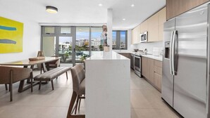 A modern kitchen with a central island, stainless steel appliances, and a dining area with benches. - Poolfront penthouse by beach (Carolina)