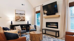 A modern living room with a fireplace, a large flat-screen TV, and a comfortable seating area.