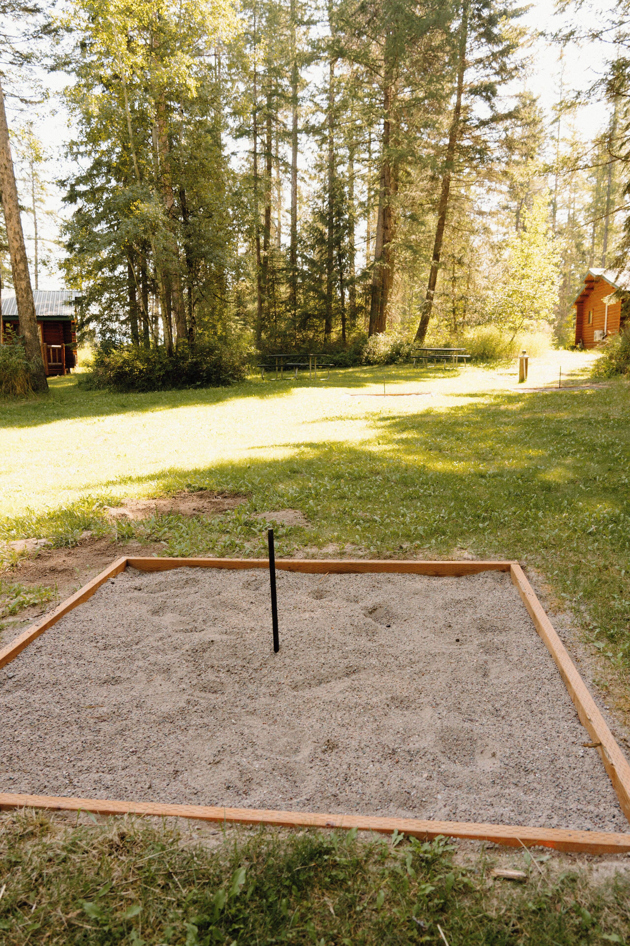 A sandbox in a grassy area with trees in the background.