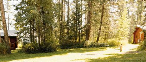 A sandbox in a grassy area with trees in the background.