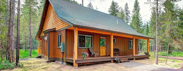 A log cabin with a porch, large windows, and a chimney. - North Forty Resort (Columbia Falls)