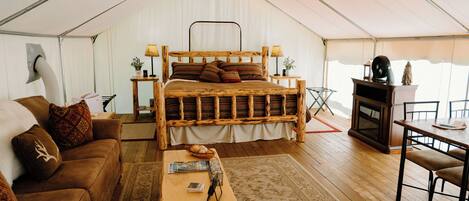 Alojamiento con carpa, una cama de madera, un sofá, una mesa y una chimenea.
