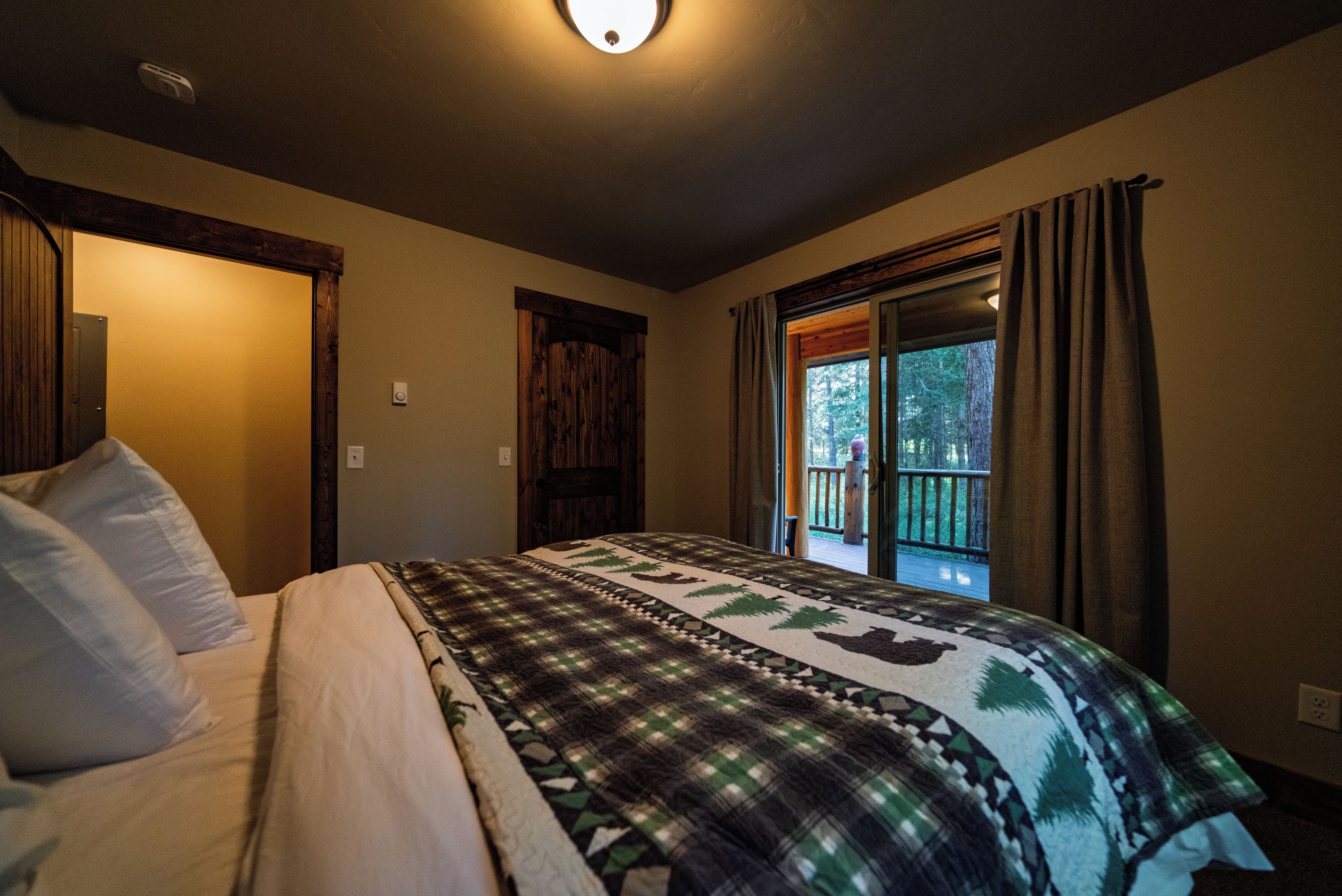 Un dormitorio con cama, ventana con cortinas y puerta.