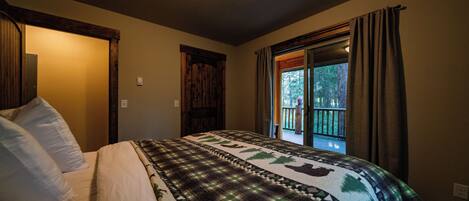 Un dormitorio con cama, ventana con cortinas y puerta.