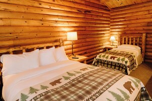 A log cabin room with two beds, each with a different style of bedding.