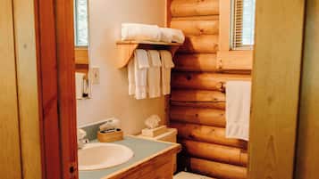 Une salle de bain rustique, aménagée dans un chalet en bois, avec un meuble-lavabo, un lavabo et des toilettes, le tout en bois.
