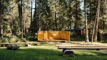 Un banco de madera en un área boscosa con mesas de picnic y una terraza de madera.