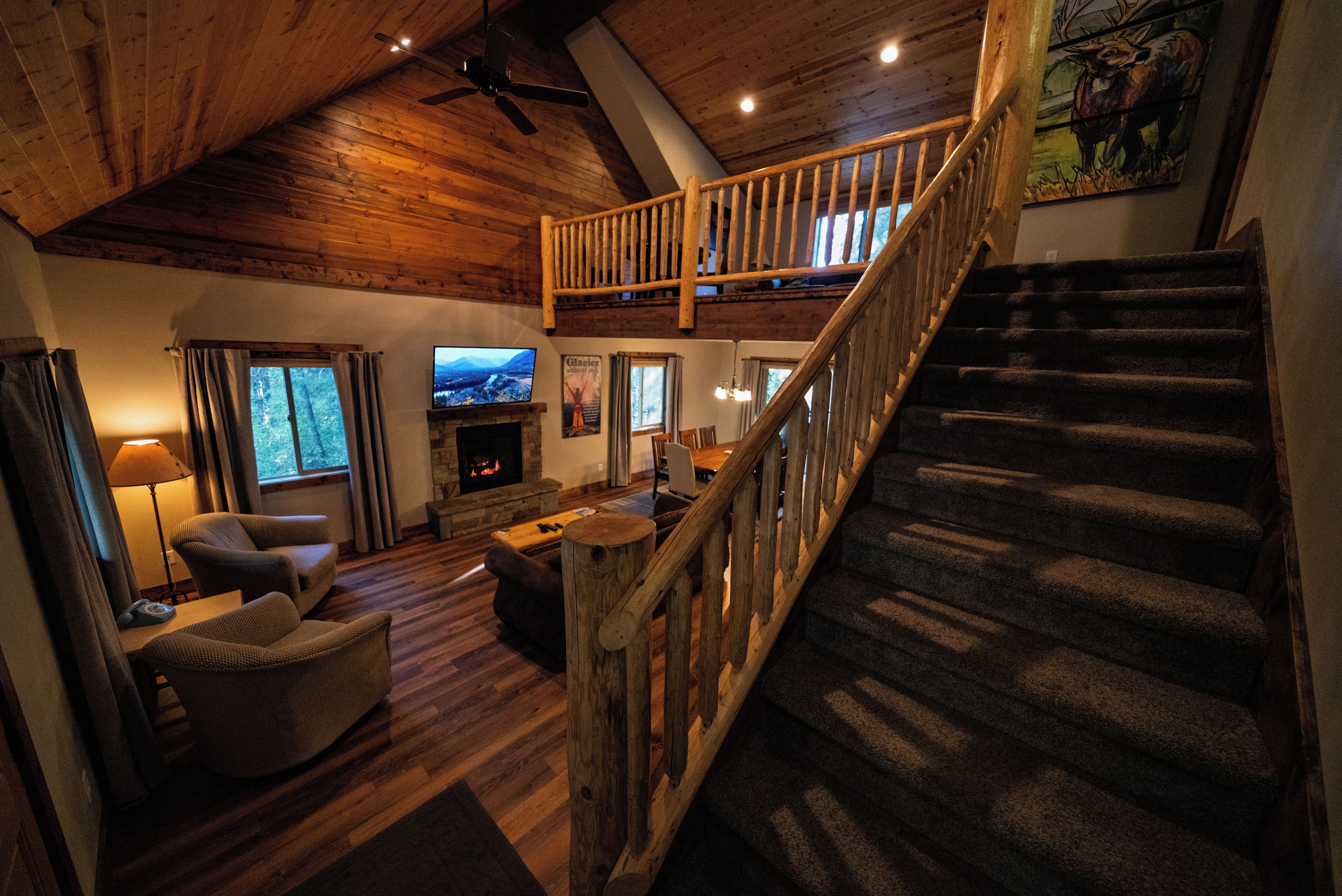 A spacious living area with a fireplace, comfortable seating, a television, and a staircase leading to an upper level.