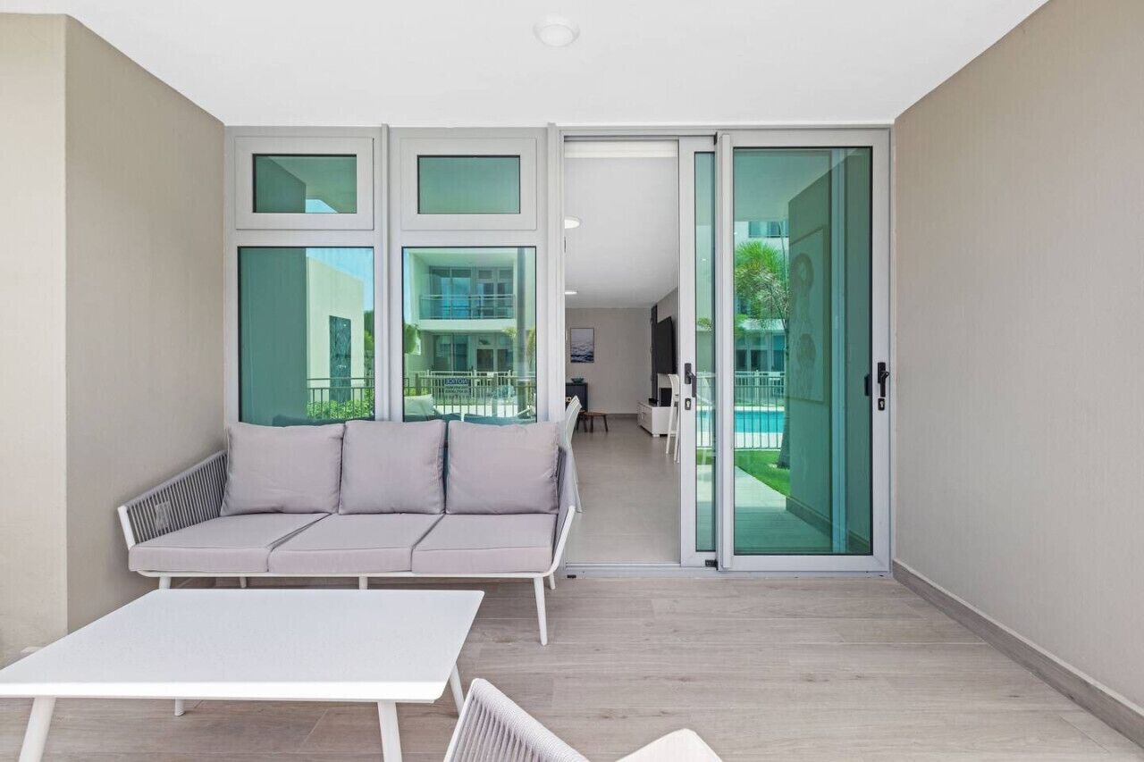 Un apartamento moderno con sofá, una mesa y un ventanal corredero que da a un balcón.