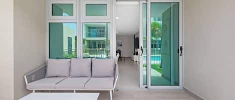Un apartamento moderno con sofá, una mesa y un ventanal corredero que da a un balcón.