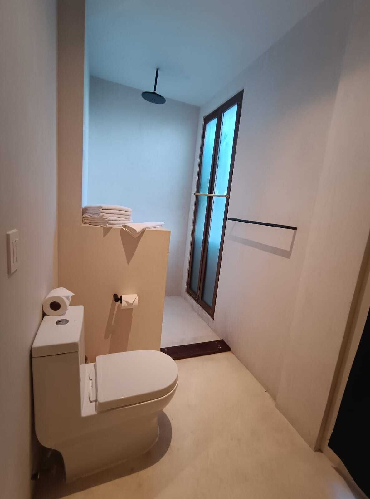 A compact bathroom with a toilet, a small window, and a ceiling fan.