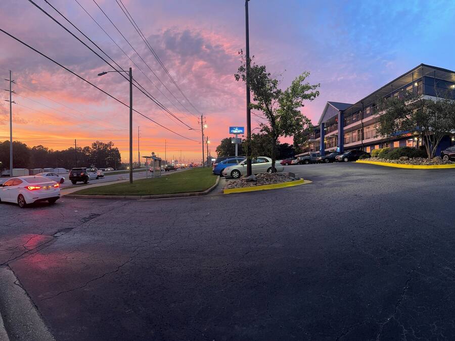A parking lot with multiple cars and a building with a blue sign.