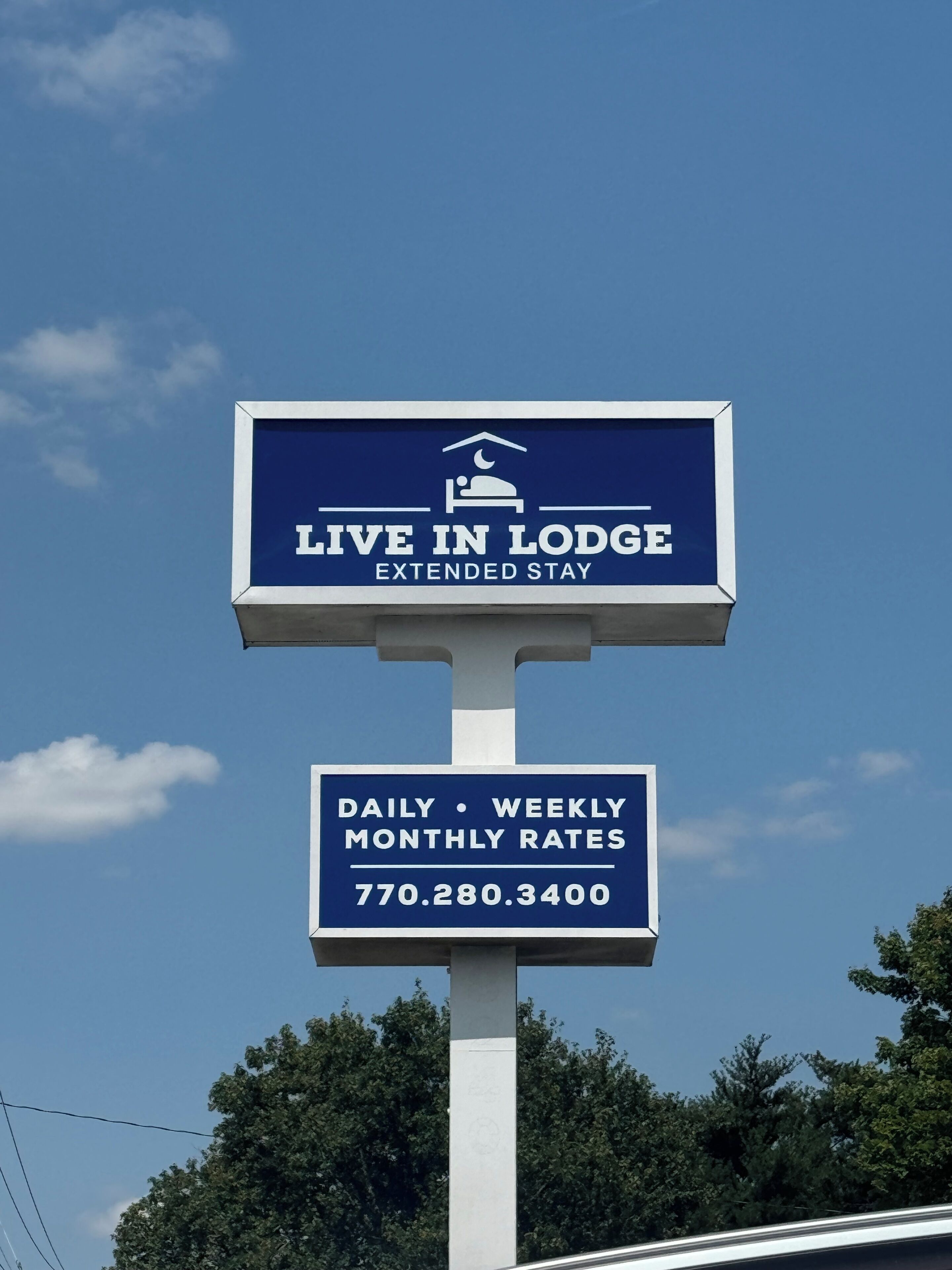 A sign for 'Live in Lodge Extended Stay' with daily, weekly, and monthly rates listed.