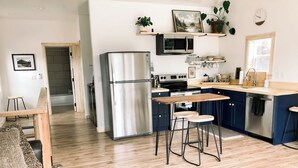 Een moderne keuken met roestvrijstalen apparatuur, een houten eettafel en barkrukken.