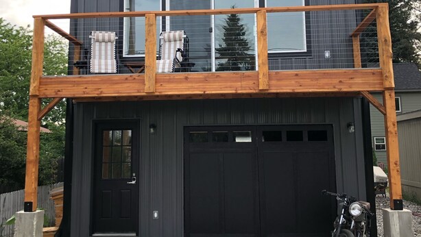 Een tweelaags huis met een balkon en een garage, met een motorfiets ervoor geparkeerd.