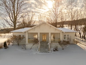 A two-story house with a front porch, a front door, and a staircase leading to the entrance. - Elegant Country Escape – Unique Home with Timeless Charm and Style (Margaretville)