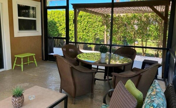 A patio area with wicker furniture, a small table, and a bench.
