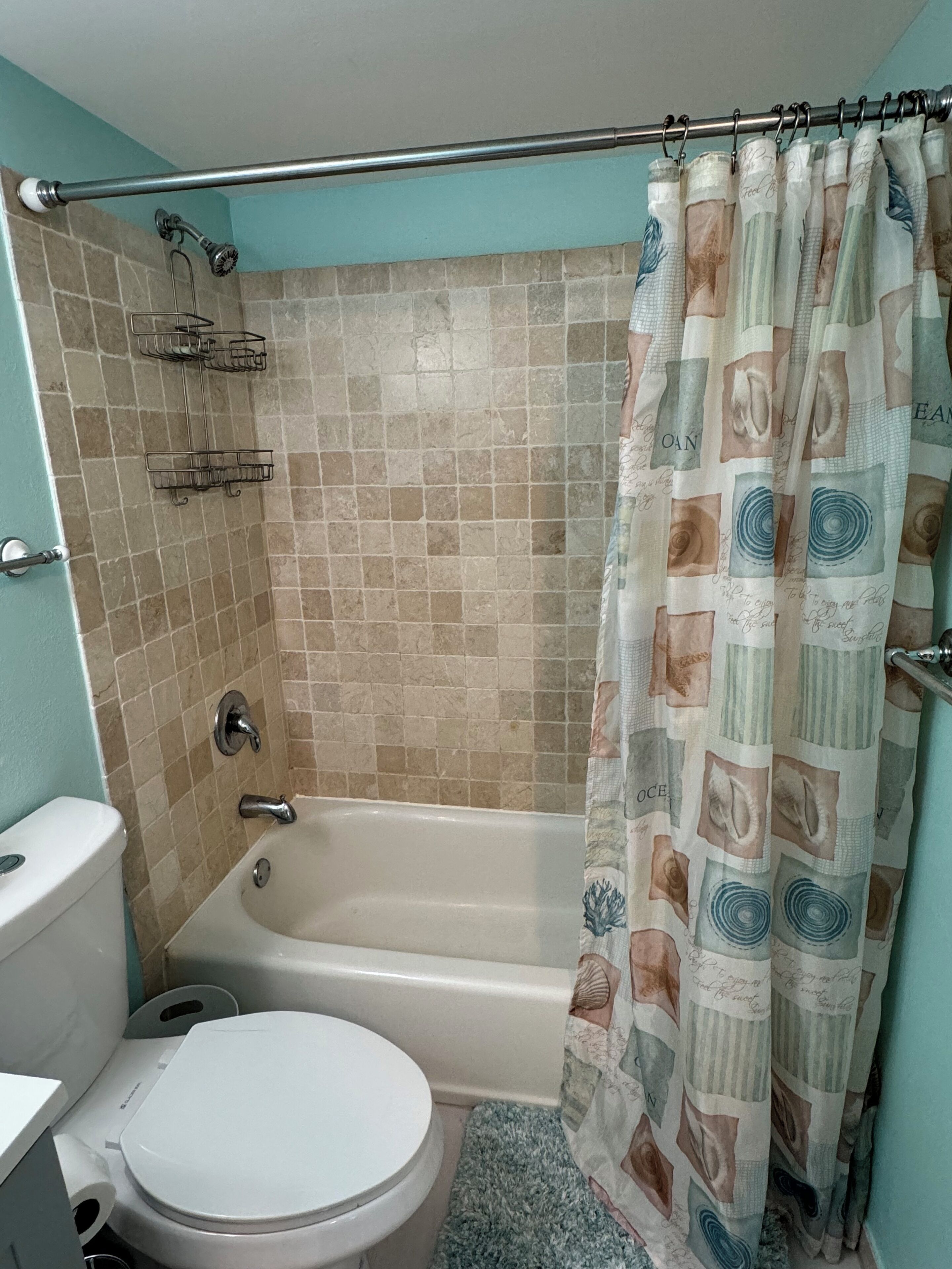 A bathroom with a bathtub, toilet, and shower curtain.